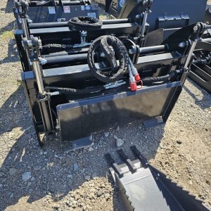 A close-up view of several BPT BobcatMT Single/Dual Clam Grapples—heavy-duty black metal attachments for construction equipment—arranged outdoors on gravel, with hydraulic hoses visible on top.