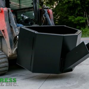 A close-up of an Express Steel Manual Concrete Placement Bucket, black steel, mounted on a red skid steer loader with trees and a road in the background. The Express Steel Inc. logo is visible in the corner.
