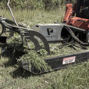 A close-up of the Prime 80" Direct Drive Brush Cutter with rotating blades, covered in branches and greenery, operating in a grassy field. A warning label on the machine reads DANGER STAY BACK 300 FEET.